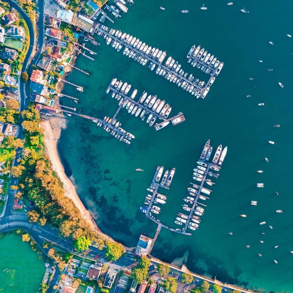 aerial drone footage of a marina with rows of boats docked beside the wharves
