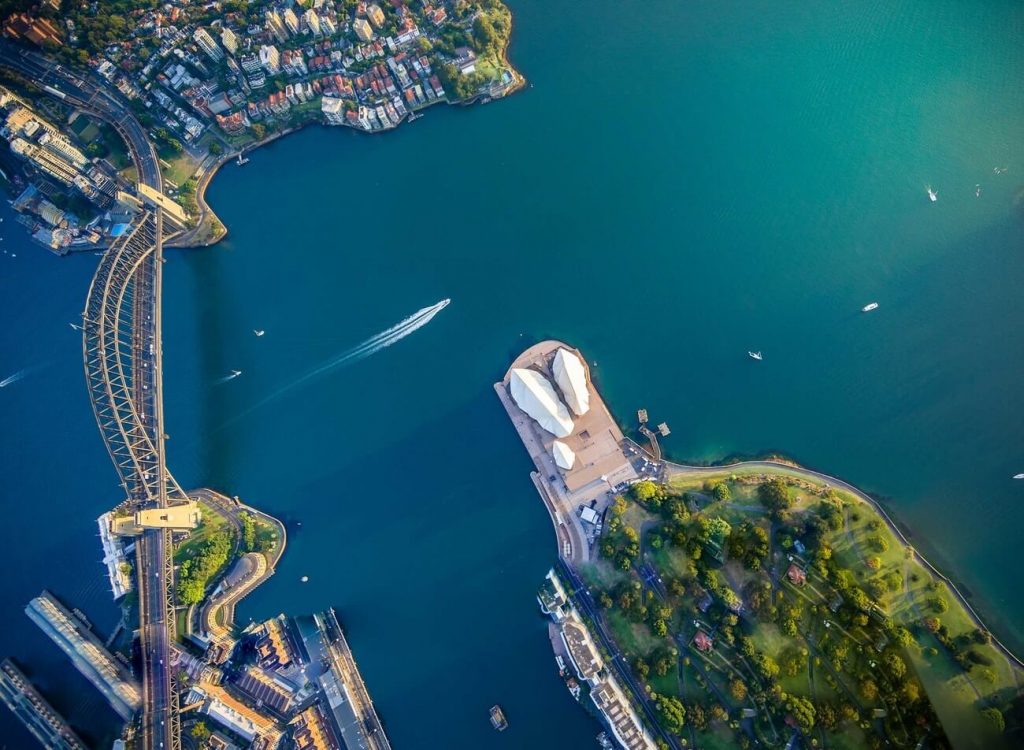 top down view of the sydney opera house and harbour bridge, with boats floating on the harbour